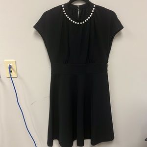 Women’s beautiful black dress with pearls around the neck.